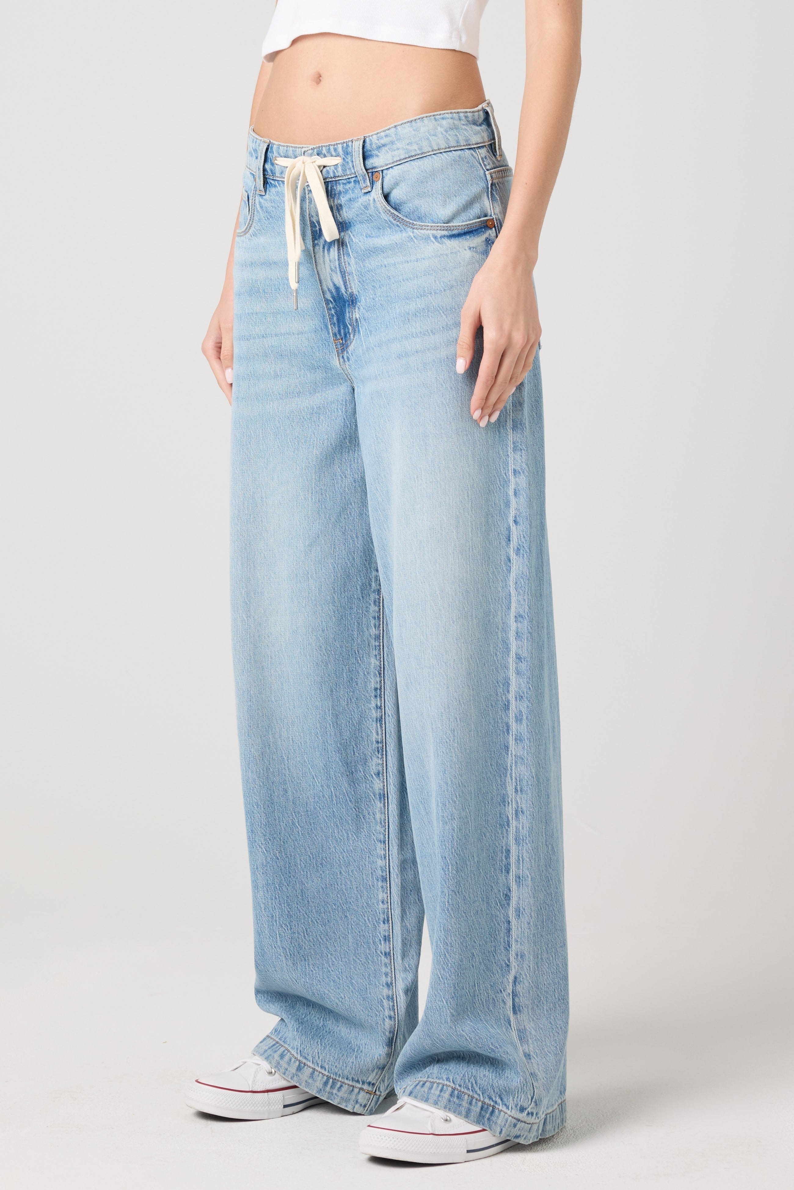 Front side view of a model wearing the BLANKNYC Feeling Good Low-Rise Baggy Fit Denim Jean in Light Indigo.