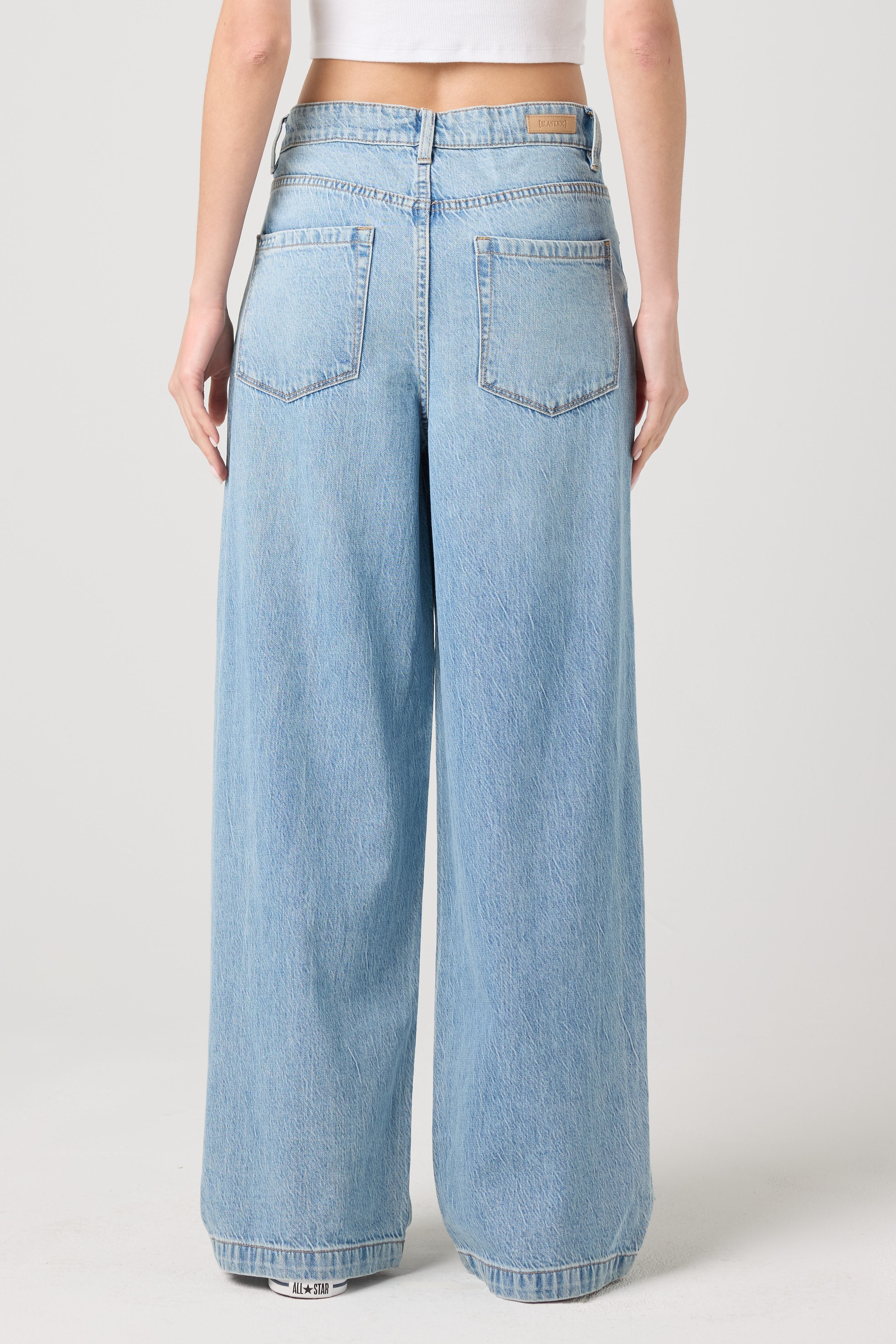 Side view of a model wearing the BLANKNYC Feeling Good Low-Rise Baggy Fit Denim Jean in Light Indigo.
