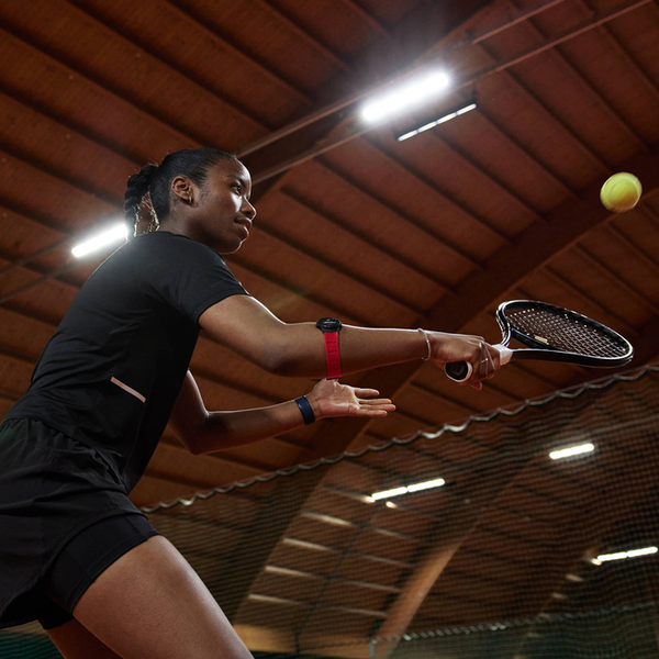 Close-up of the MYZONE MZ-Switch heart rate monitor on arm strap of woman playing tennis