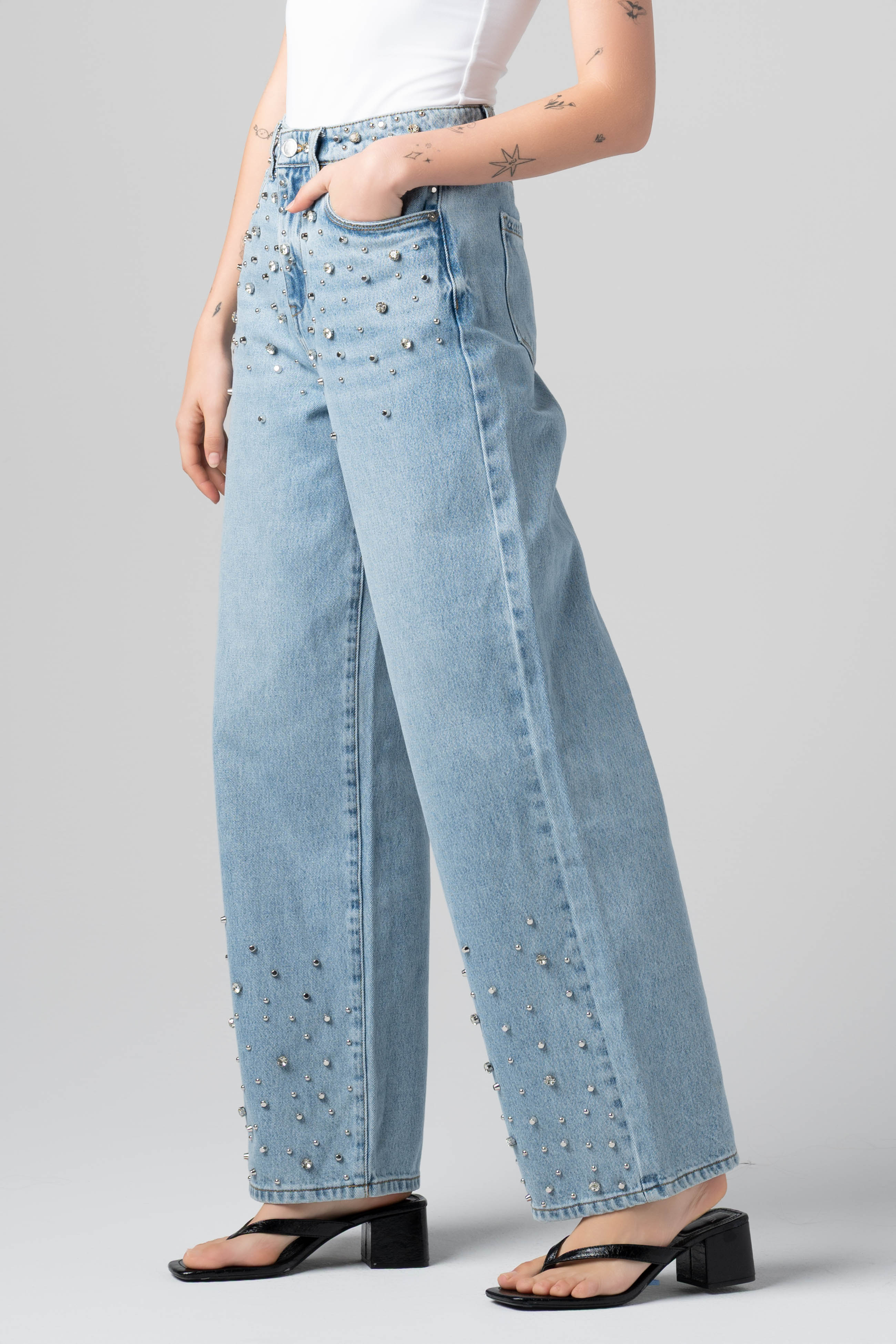 Side view of a model wearing the BLANKNYC Diamonds in the Sky Jean in Light Indigo with rhinestone embellishments.
