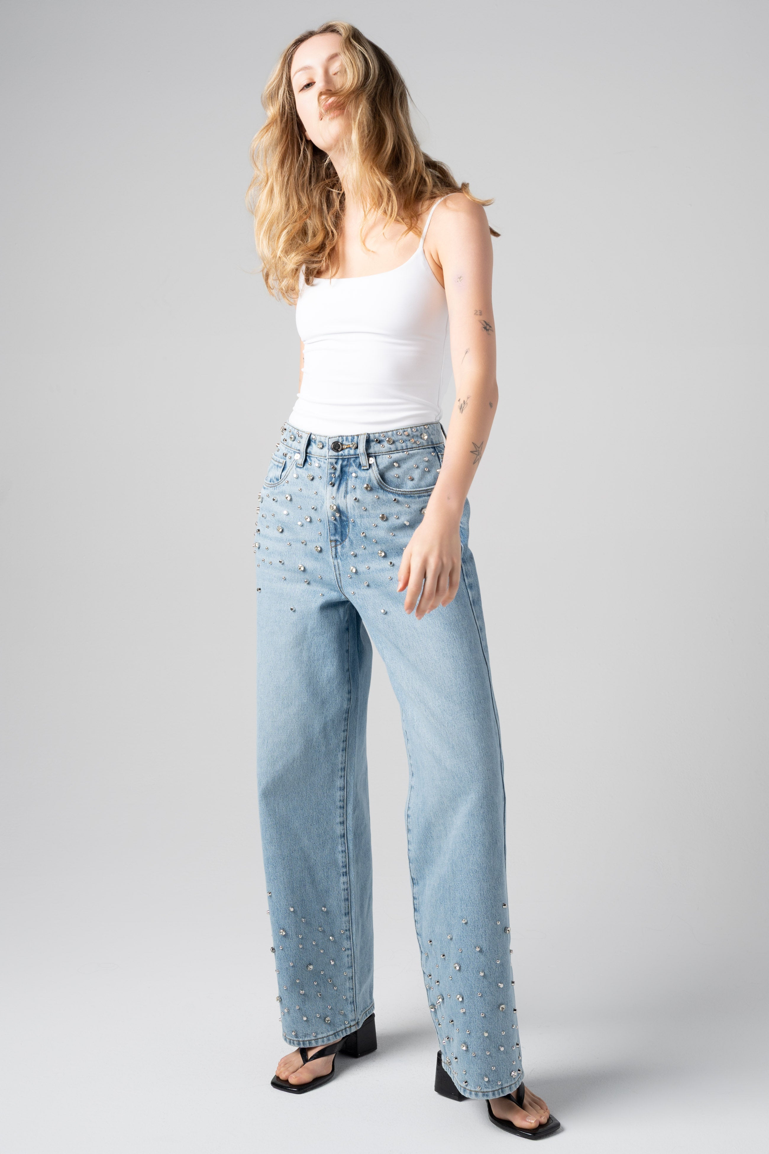Model wearing the BLANKNYC Diamonds in the Sky Jean in Light Indigo with rhinestone embellishments, front view.