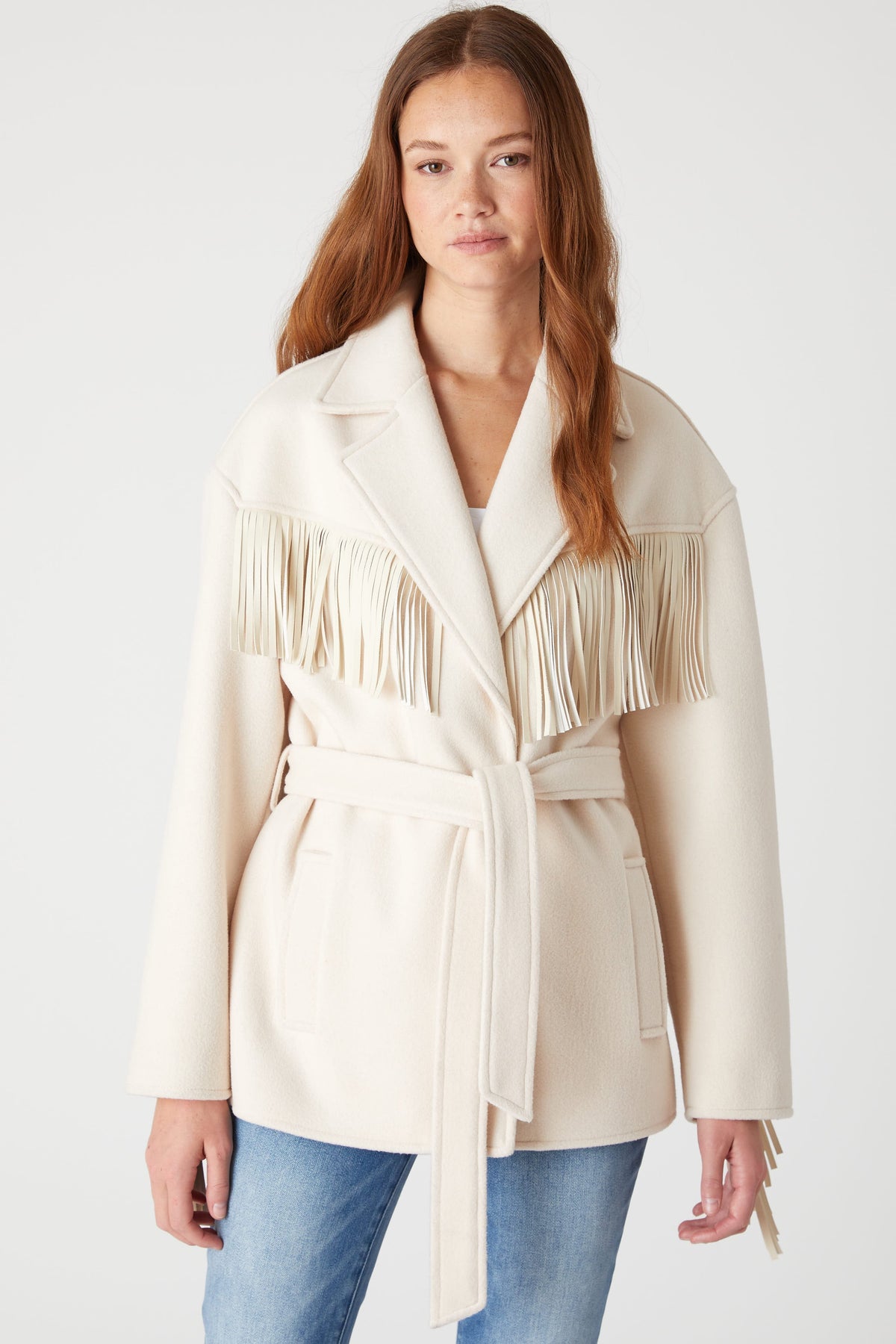 Front view of a model wearing the BLANK NYC Rodeo Star Blazer in Off White, showing fringe and the tied waist belt.