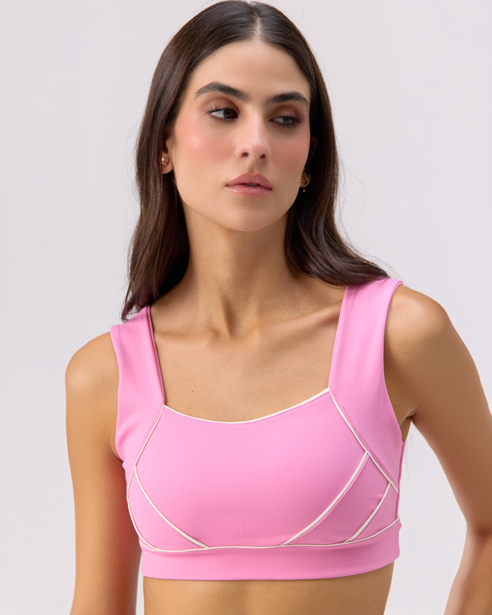 Close-up of model wearing Glee x Be Fit bubble gum pink athletic sports bra with white accents.
