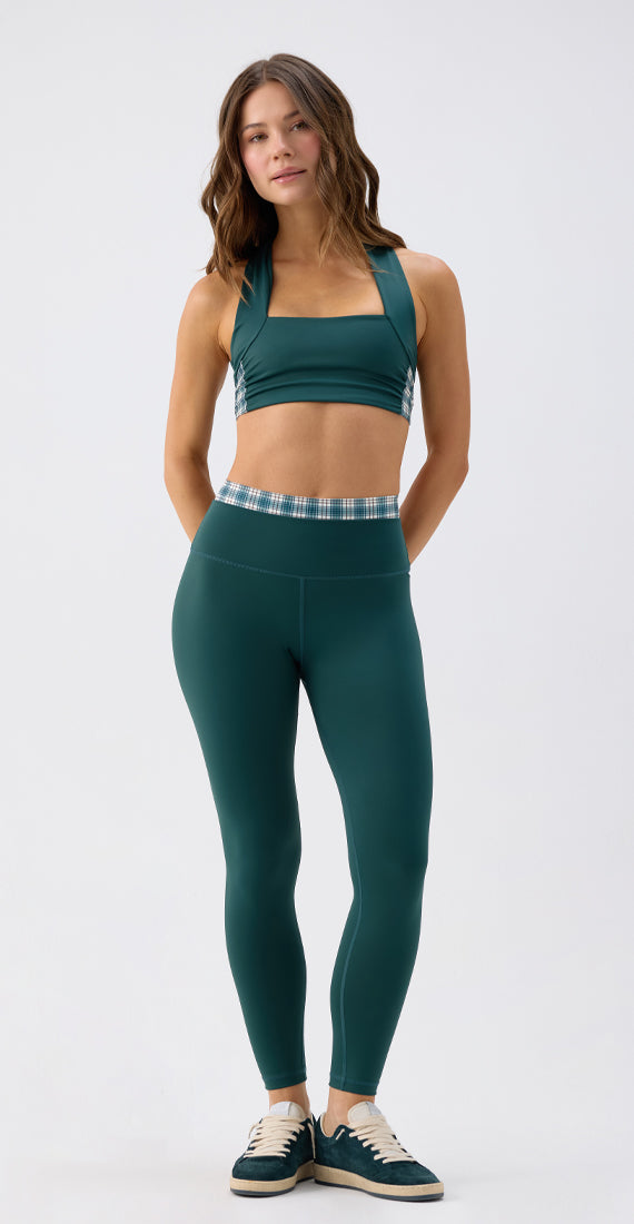 Front view of a model wearing the Be Fit x Glee Verdant Leggings with a matching botanic green Elysian sports bra top and plaid details.