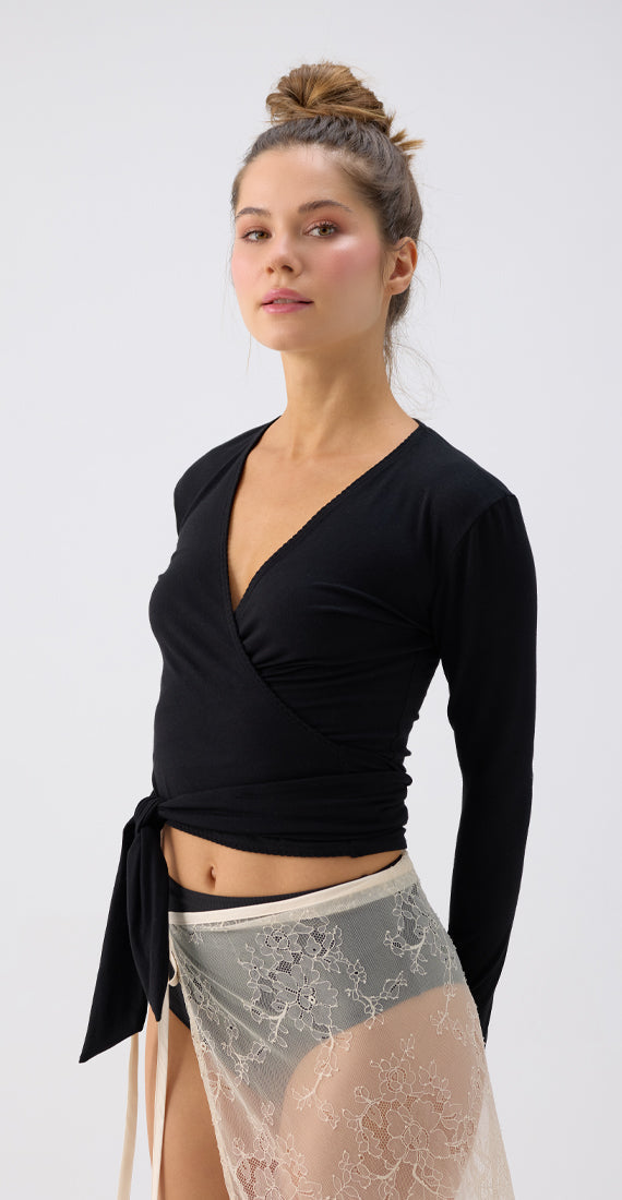 Angled view of a model wearing the black onyx Be Fit x Glee Ballerina Wrap with a crossover front and side waist tie.