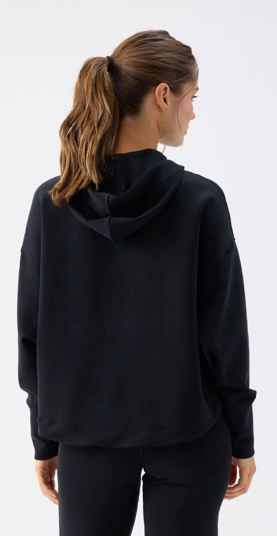 Back view of a model wearing the Be Fit x Glee black Onyx Raincoat with a relaxed fit and hood.
