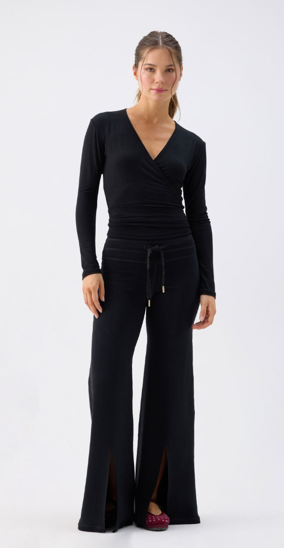 Front view of model wearing black onyx Be Fit x Glee Leggings Flare Soft Motion with front hem slits and a matching long-sleeve Ballerina Wrap top.