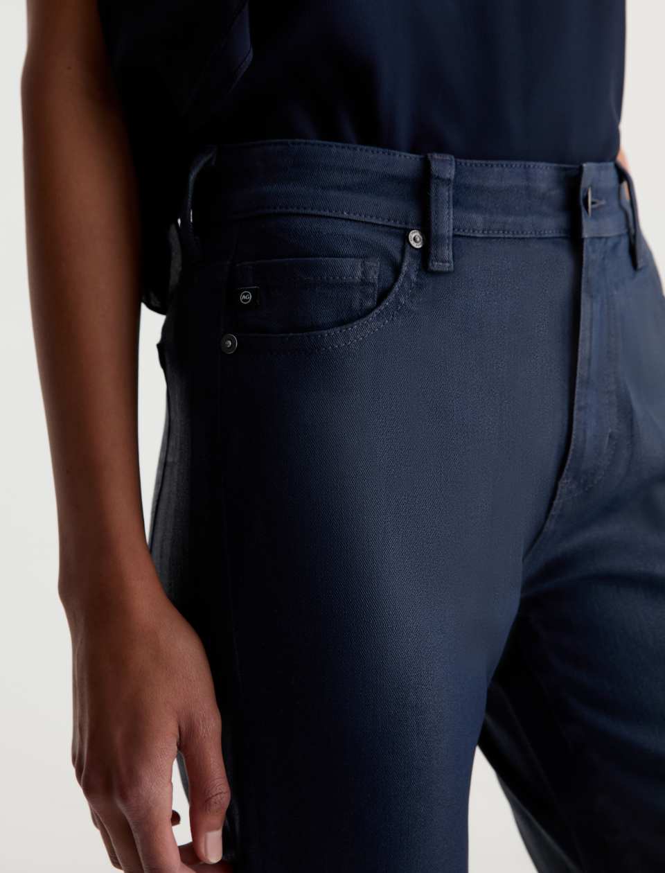 Close-up of the AG Mari Coated Jean’s front pocket, waistband and softly glossed finish.