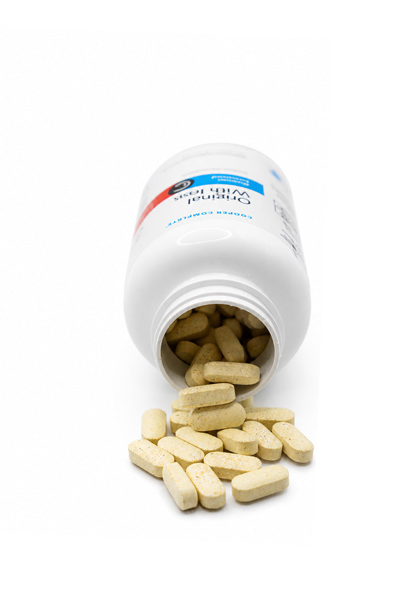 Open white Cooper Complete Original Comprehensive With Iron Multivitamin pill bottle with tablets spilling out on a white background