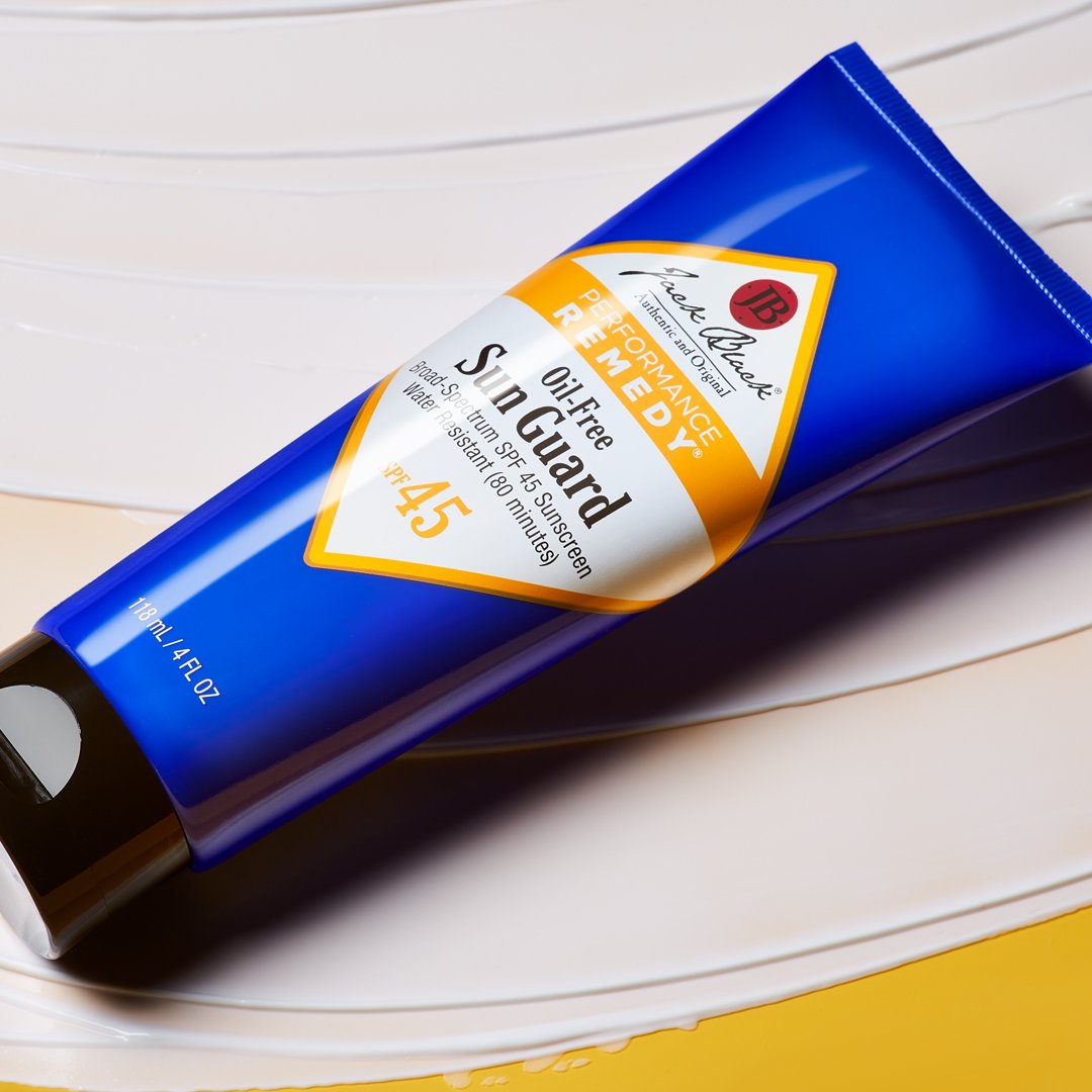 Jack Black Oil-Free Sun Guard SPF 45 4 oz blue sunscreen tube displayed on a white surface with water droplets, lifestyle product view.