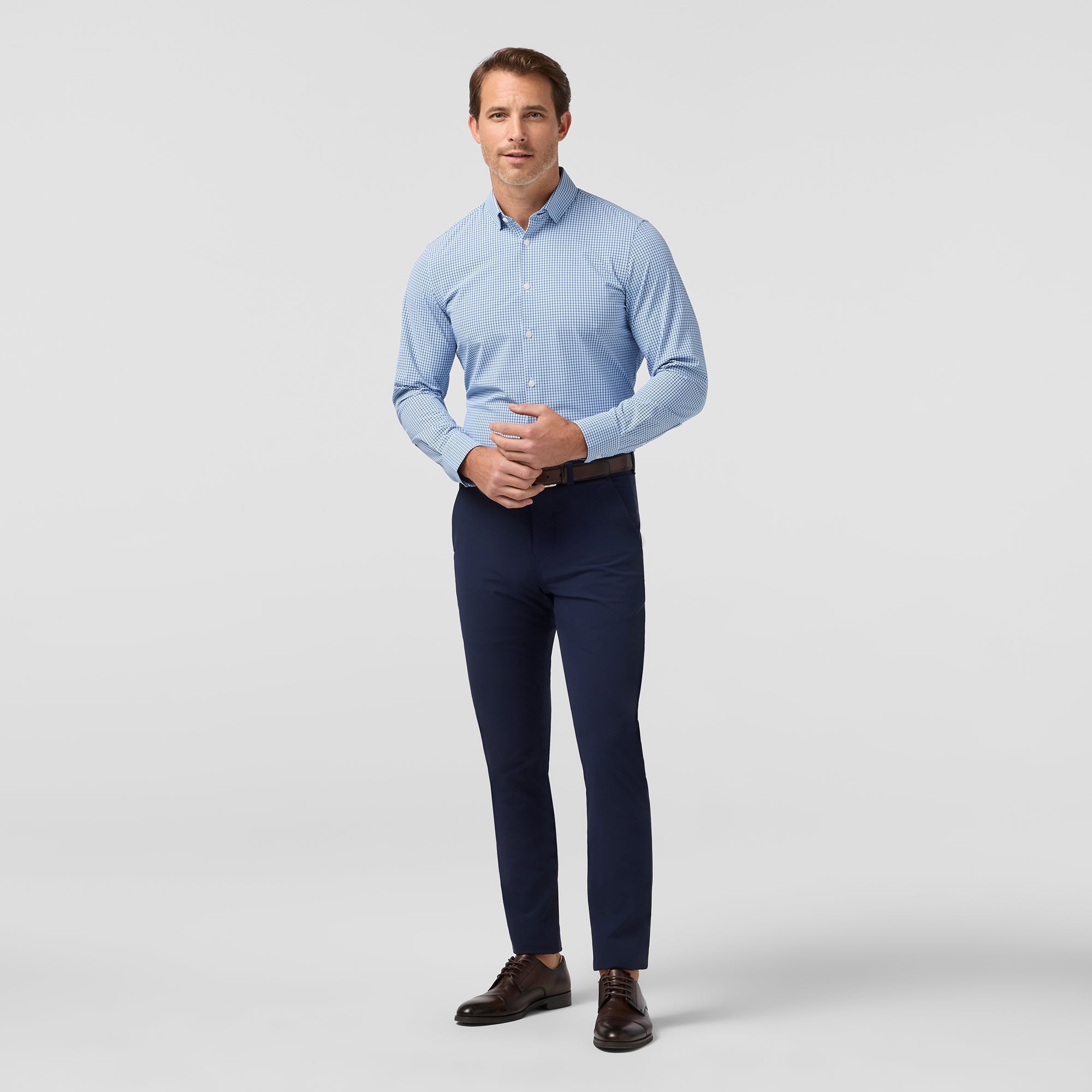 Model wearing the Mizzen+Main Leeward Long Sleeve Dress Shirt (Trim Fit) in Midnight Navy Sam Plaid (dark navy and blue plaid), showing the tailored fit and spread collar.