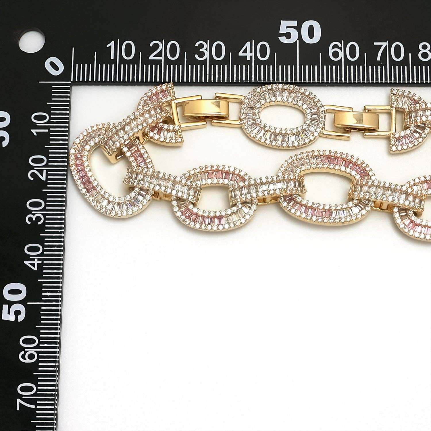 Close-up of the baguette-cut clear and blush-pink cubic zirconia centerpiece on the Simply Jewels gold-tone cable chain necklace.
