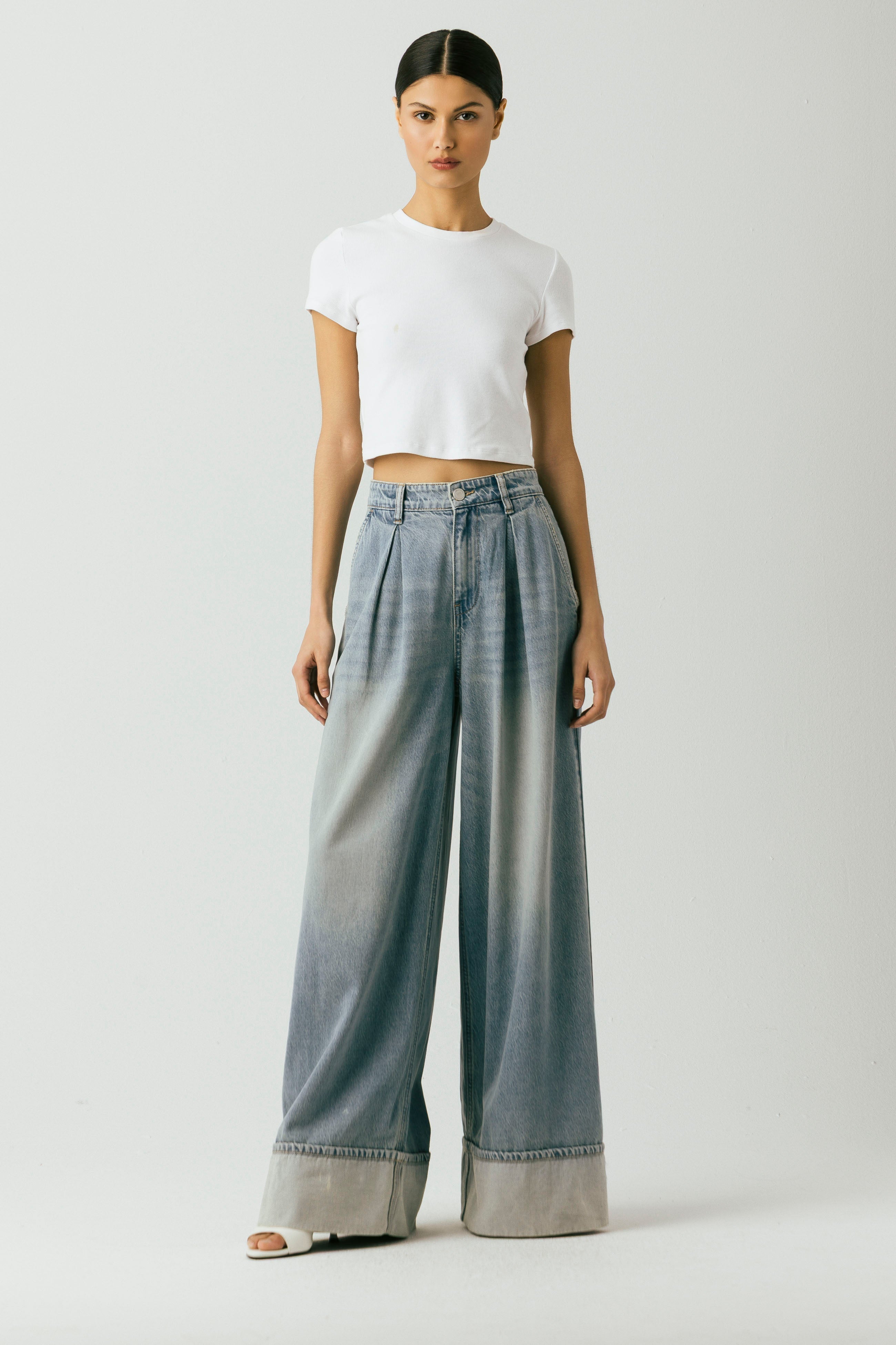 Model wearing the Blank NYC Easy Day Pleated Wide-Leg Denim Trouser in Light Indigo Creative with a white t-shirt, front view.