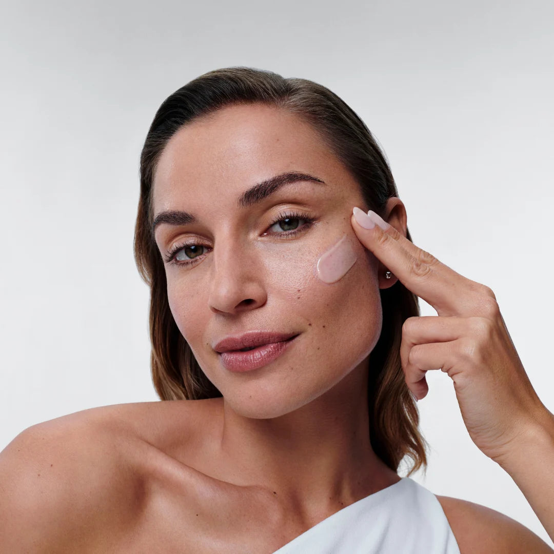 Woman with healthy-looking skin applying Alastin Restorative Skin Complex to her cheek. 
