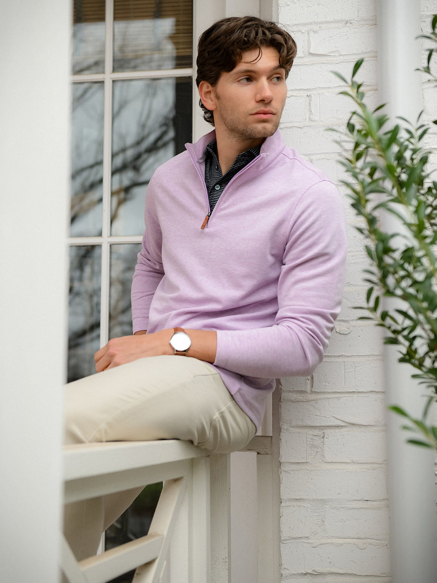 Model wearing the Mizzen+Main KPI Quarter Zip in Purple Dusk Heather (lilac) while seated on a porch, showing the lightweight layering style and relaxed appearance.