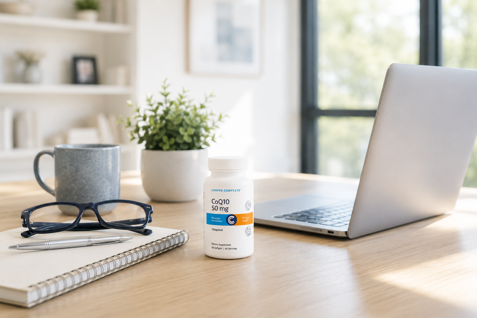 A bottle of Cooper Complete CoQ10 50 mg on a home office desk with a laptop, notebook, glasses, and coffee mug, supporting heart health and cellular energy production.