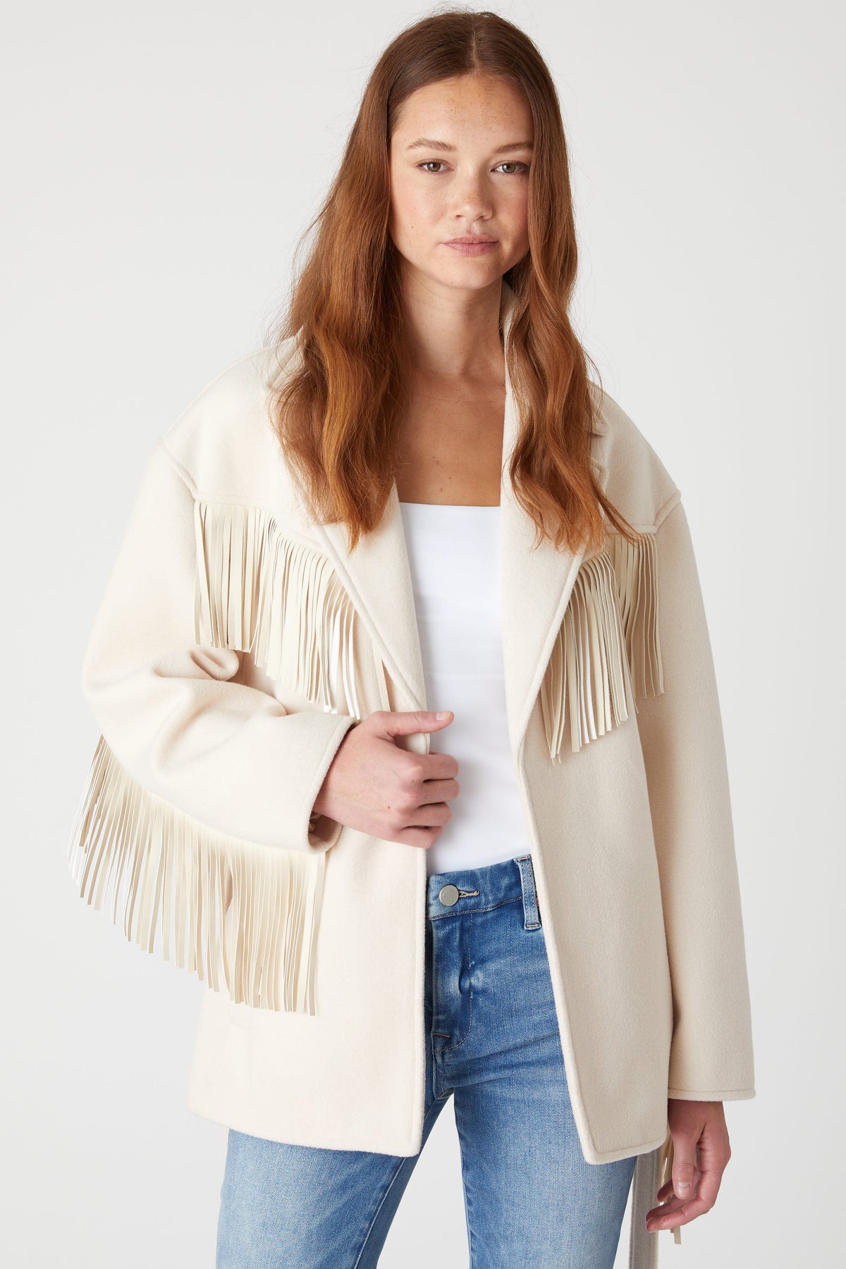 Front view of a model wearing the BLANK NYC Rodeo Star Blazer in Off White open over a white top and blue jeans.