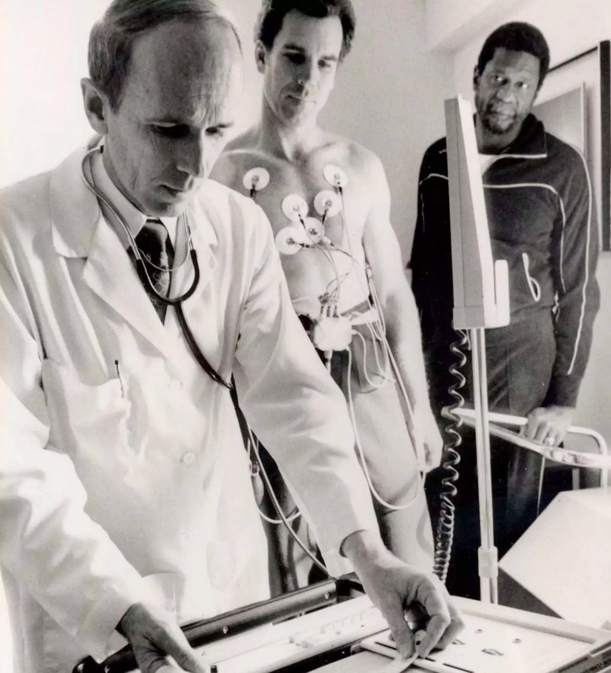 Historical photo of Dr. Kenneth H. Cooper examining an EKG reading during a clinical stress test. 
