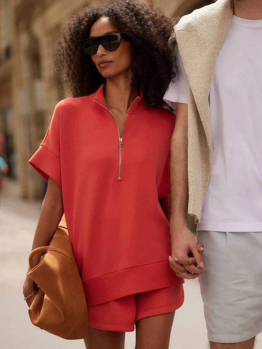Woman in a red Varley shorts outfit holding hands with another person on a street.