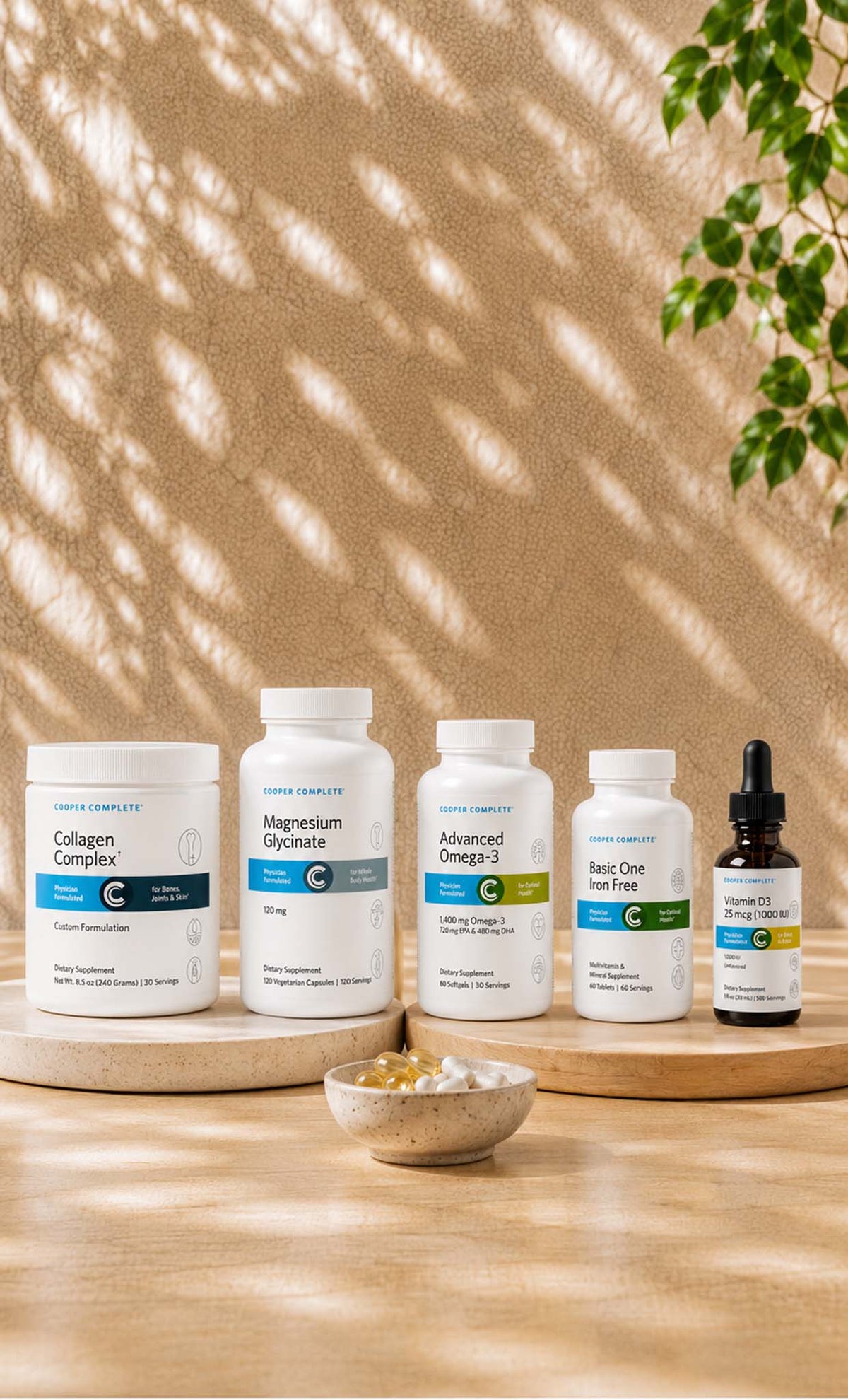Five Cooper Complete vitamin and supplement bottles on a tan surface with natural sunlight. 