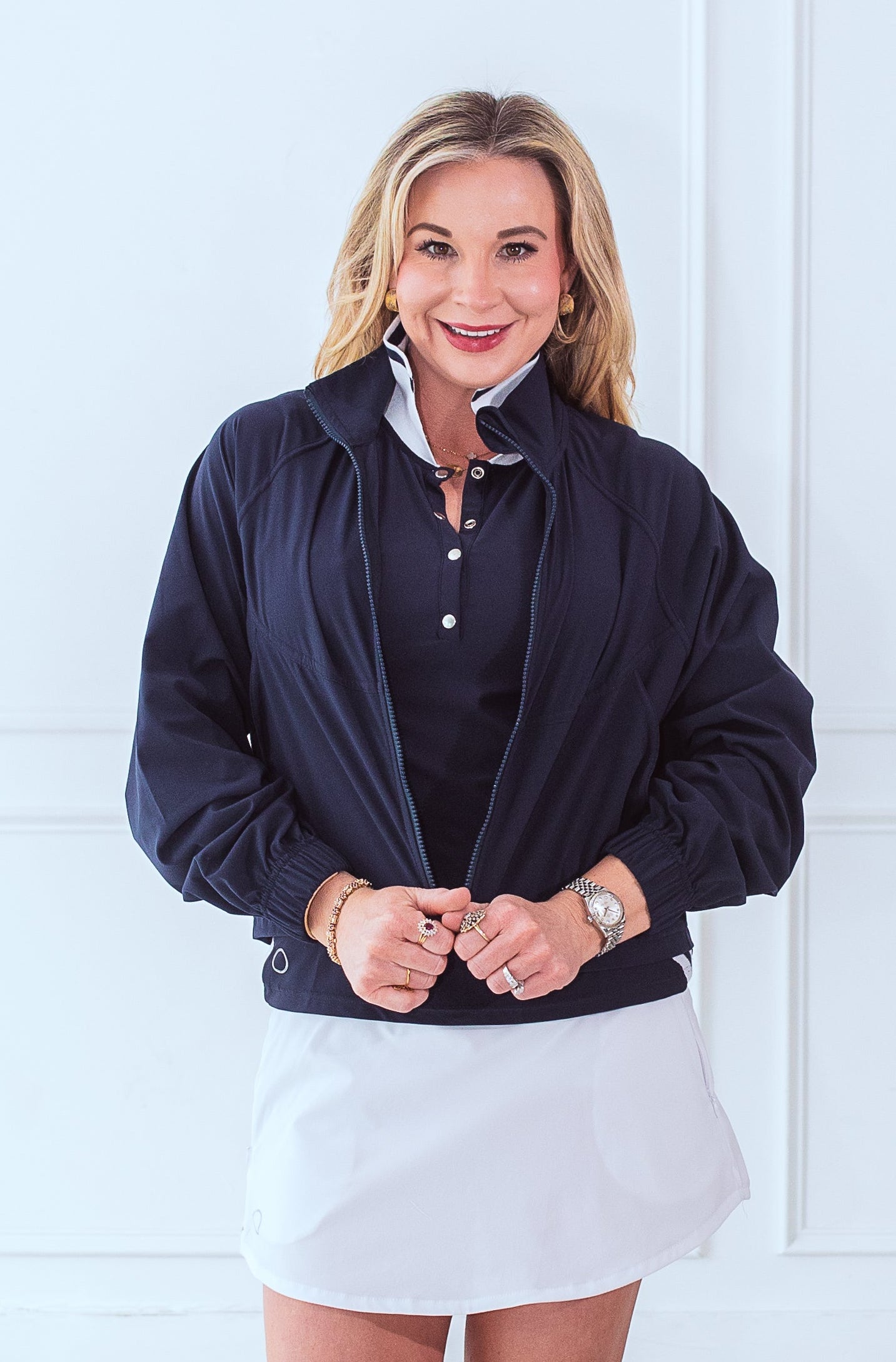 Front view of smiling, active, middle-aged woman in activewear wearing the Brooklyn Jacket in navy. 