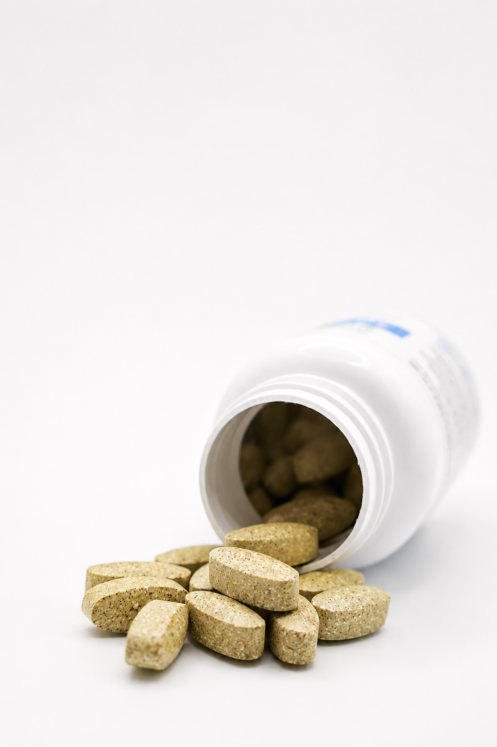 Cooper Complete Basic One With Iron Daily multivitamin tablets spilling out of a white plastic bottle on a clean white background.