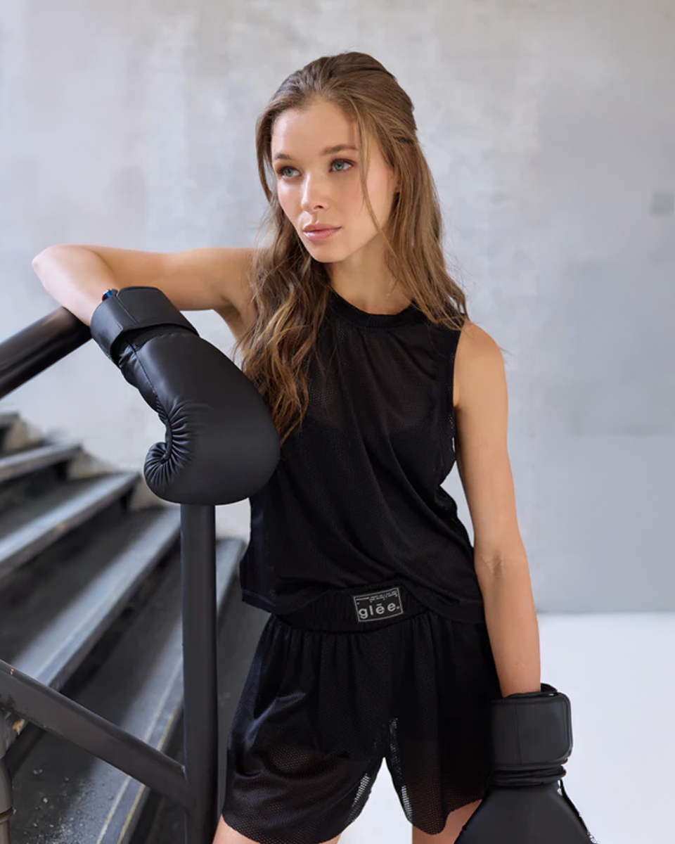 Model wearing the Glee x Be Fit Boxing Mesh Short in navy, front view, with boxing gloves at the gym.
