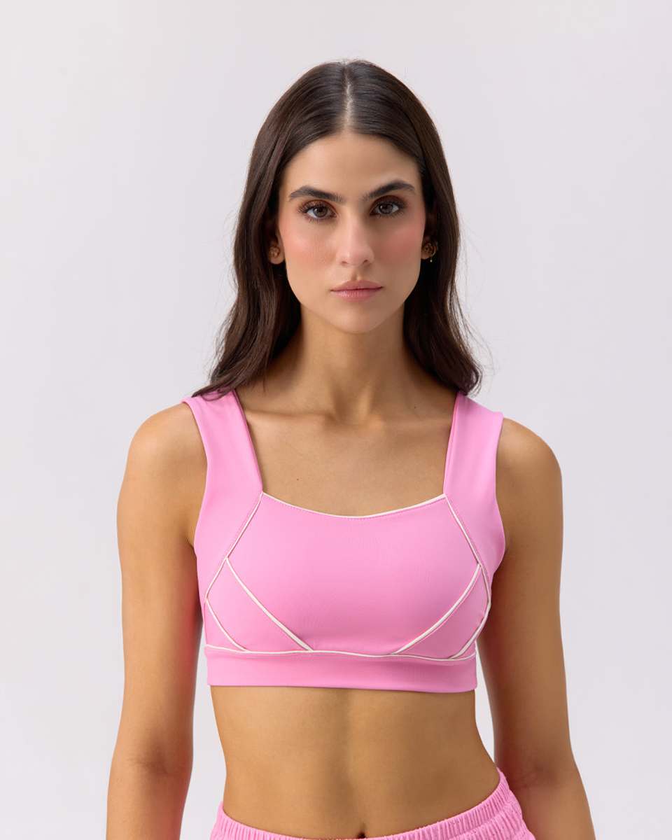 Close-up of model wearing Glee x Be Fit bubble gum pink athletic sports bra with white accents.