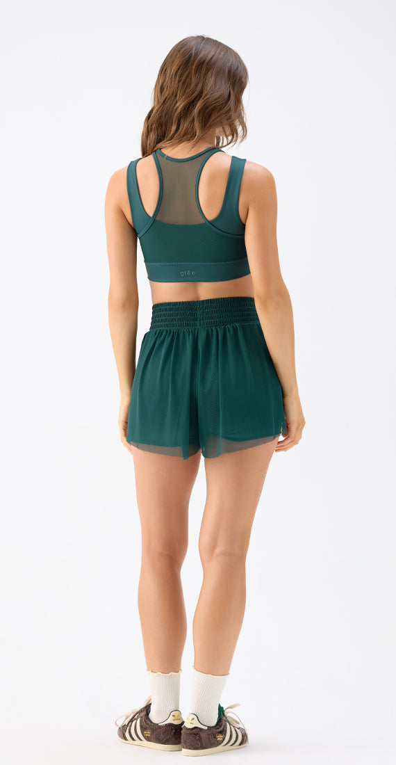 Back view of a model wearing the Be Fit x Glee botanic green Ballerina Mesh Shorts, highlighting the wide waistband and layered mesh design.