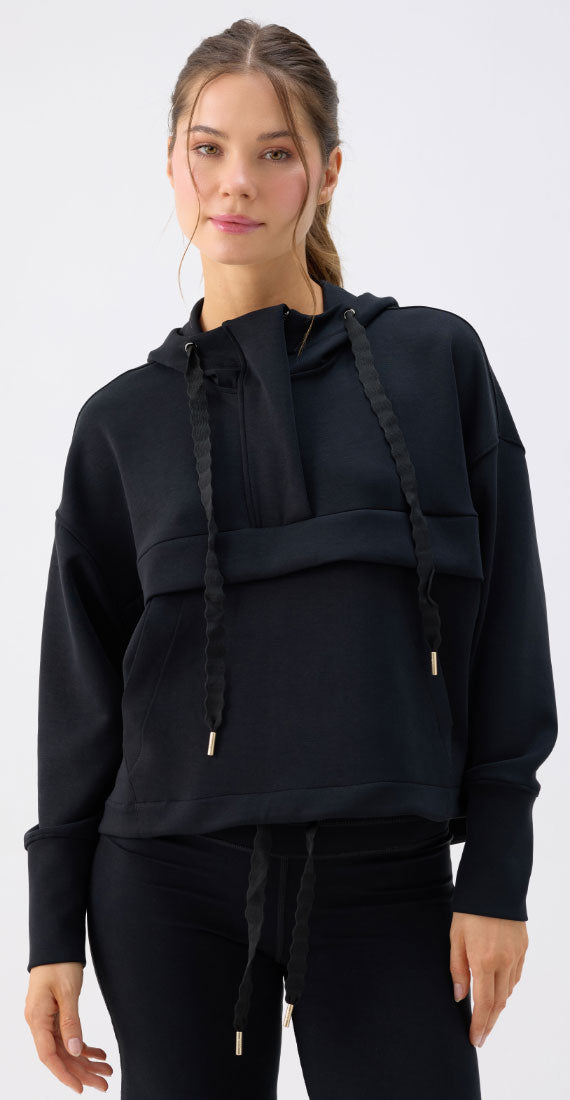 Model wearing the Be Fit x Glee black Onyx Raincoat with a hood, braided drawstrings and relaxed silhouette.