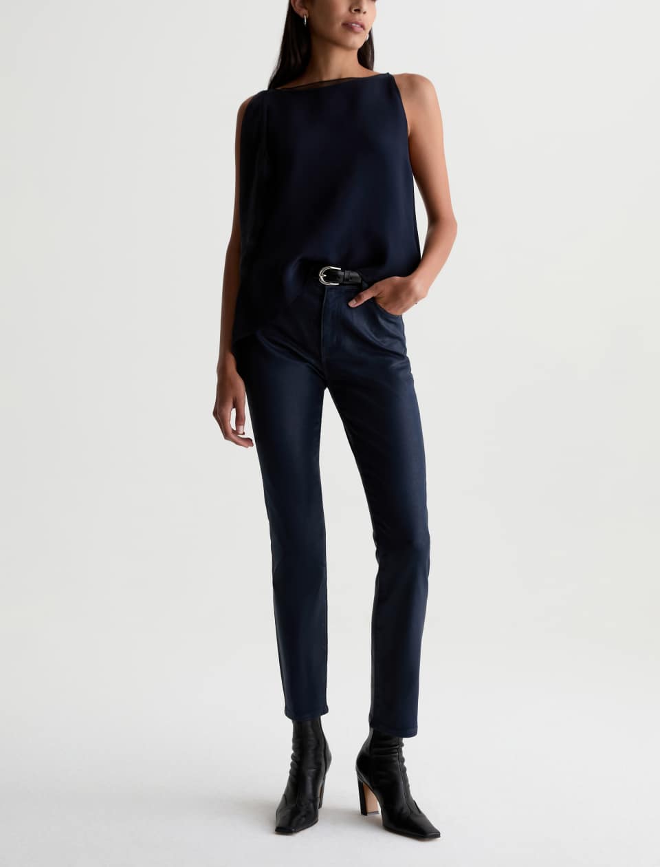 Model wearing the AG Mari Coated Jean with a navy sleeveless top, black belt and ankle boots.