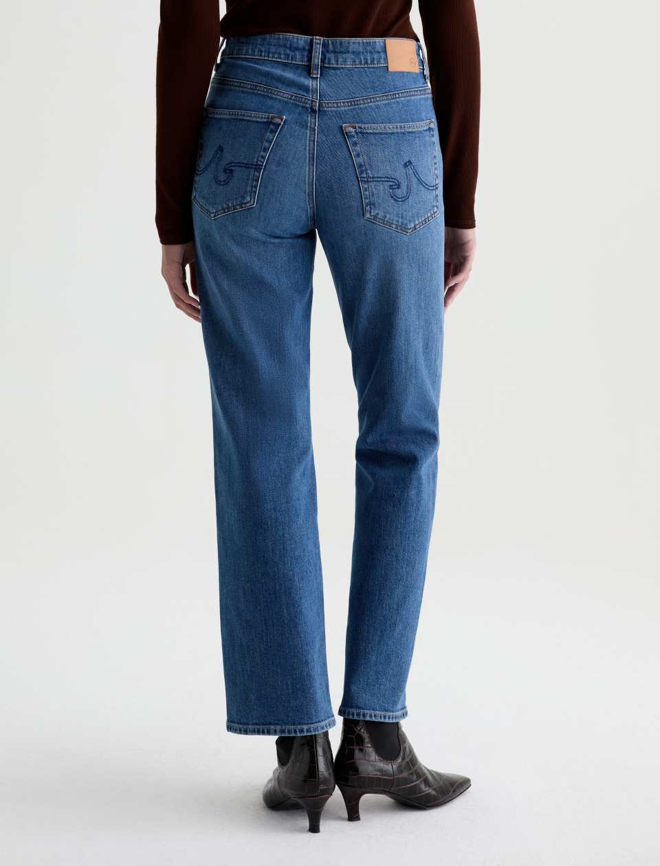 Back view of the AG Jeans Brinley Mid-Rise Jean in Chord on a model, showing the embroidered back pockets and the AG waistband patch.