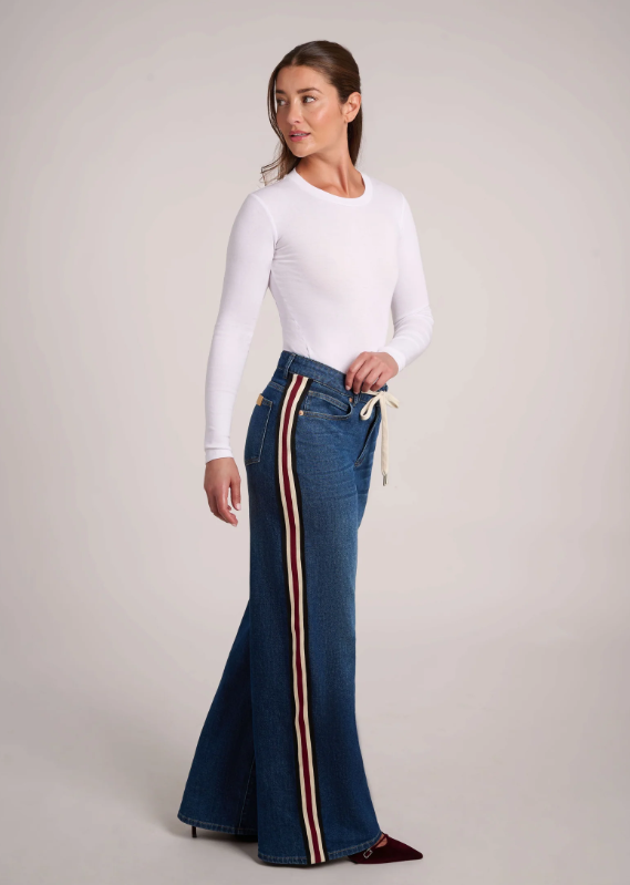 Side view of the Carina High Rise jeans showing the red, white and black stripe running down the outer leg.