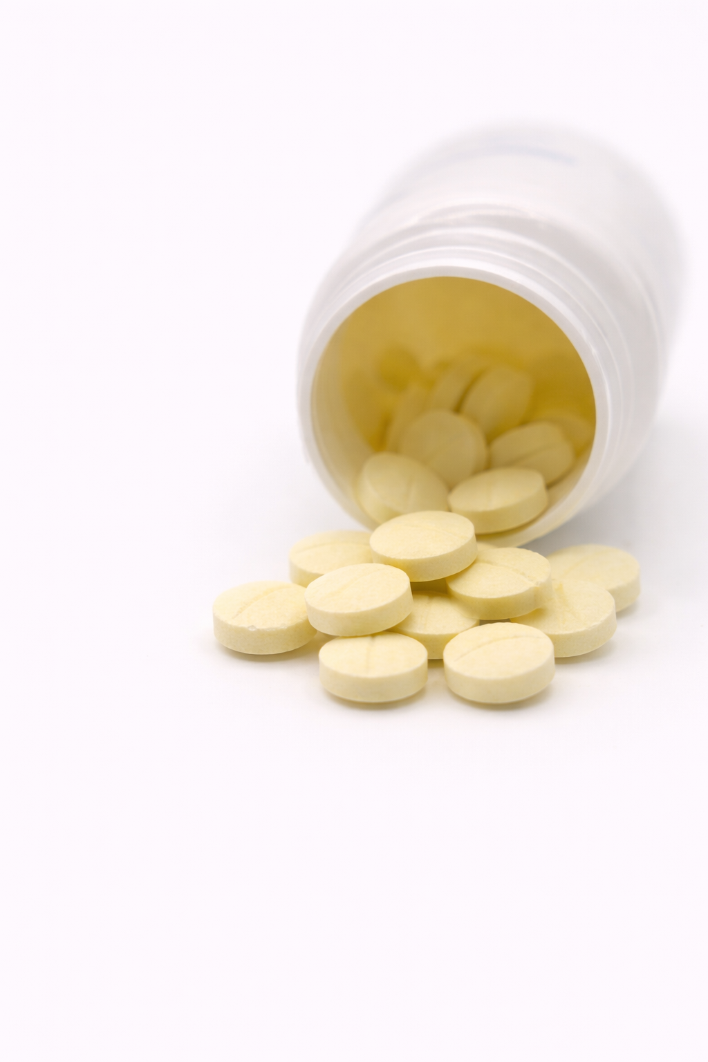 Bottle of Cooper Complete Quick Release Melatonin round tablets spilling out onto a white background.