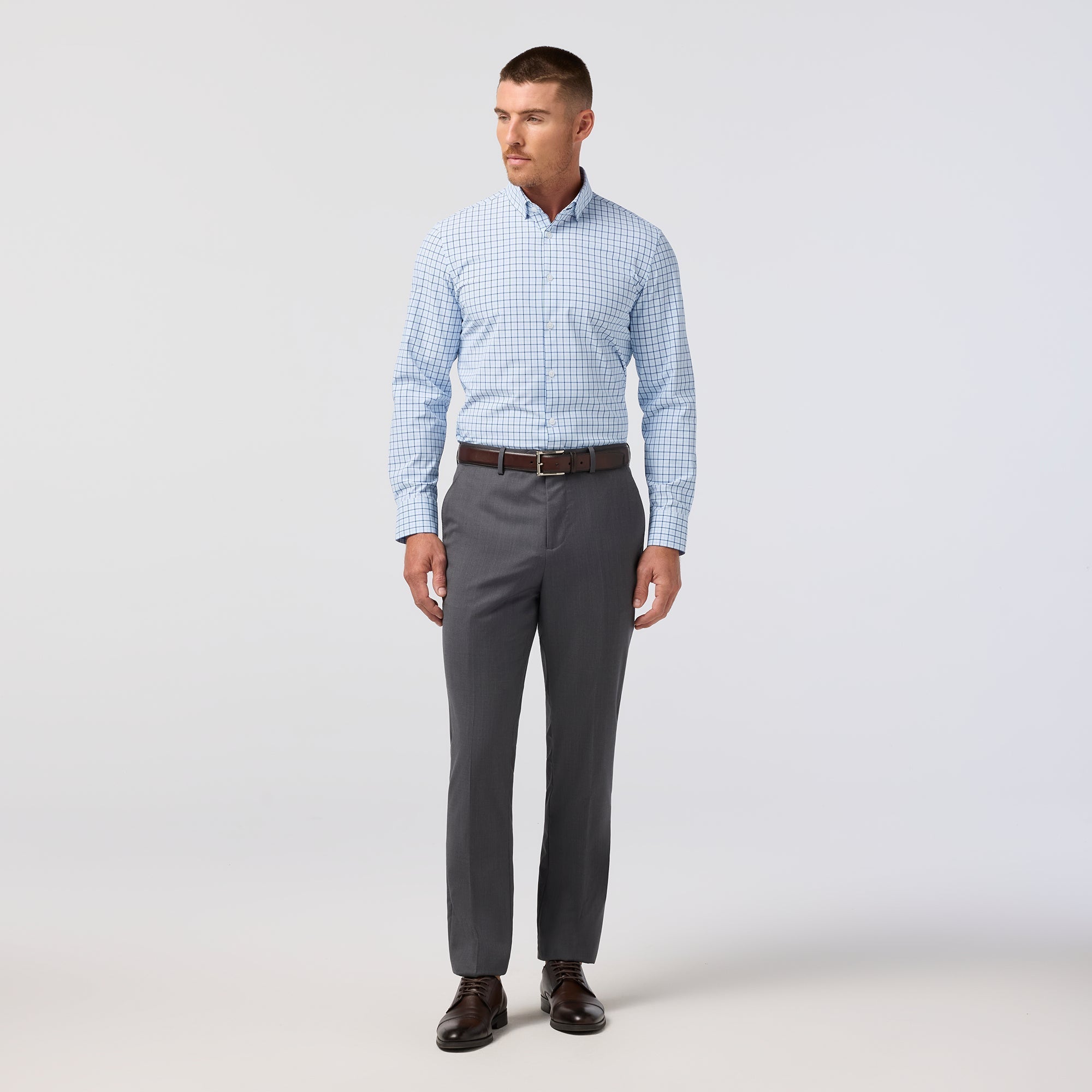 Model wearing the Mizzen+Main Leeward Long Sleeve Dress Shirt (Trim Fit) in Cloud Blue Wyatt Plaid (light blue and white plaid), showing the tailored fit and spread collar.
