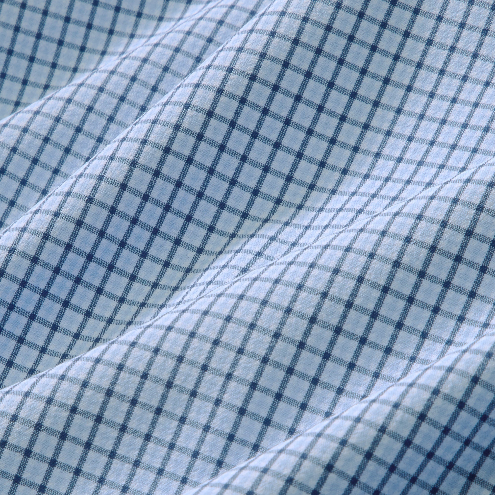 Fabric swatch of the Mizzen+Main Leeward Long Sleeve Dress Shirt in Midnight Navy Sam Plaid (dark navy and blue plaid), showing the lightweight four-way stretch performance fabric and plaid pattern.