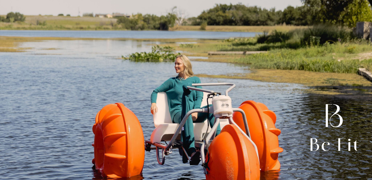 Woman wearing a teal Be Fit long sleeve top and matching pants on a pedal boat with orange wheels on a lake.