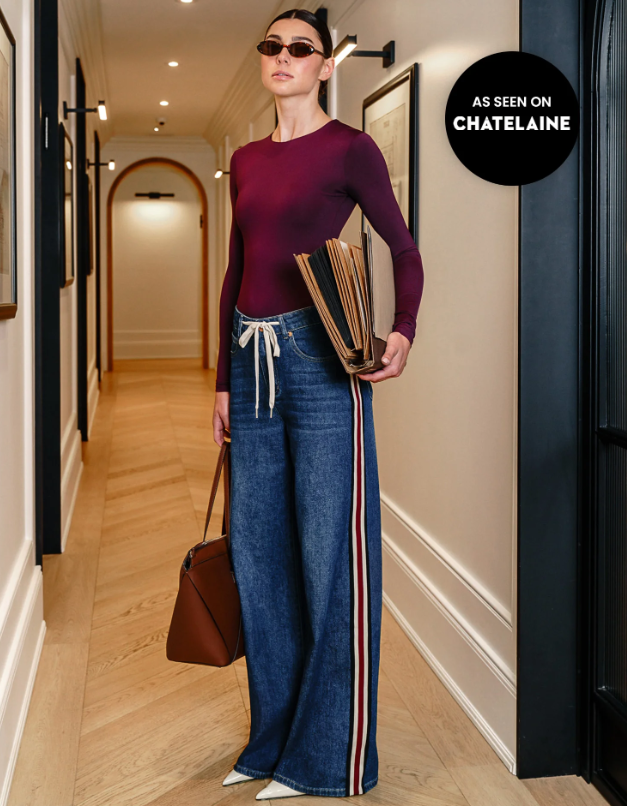 Model wearing Yoga Jeans Carina High Rise jeans with a burgundy top, showing the drawstring waist and striped outer leg; “As seen on Chatelaine” badge.