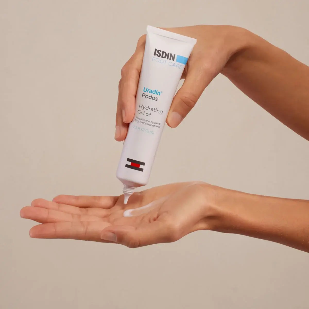 Smooth hands squeezing a bottle of ISDIN Uradin Podos Foot Care Gel Oil onto palm in front of a beige background. 