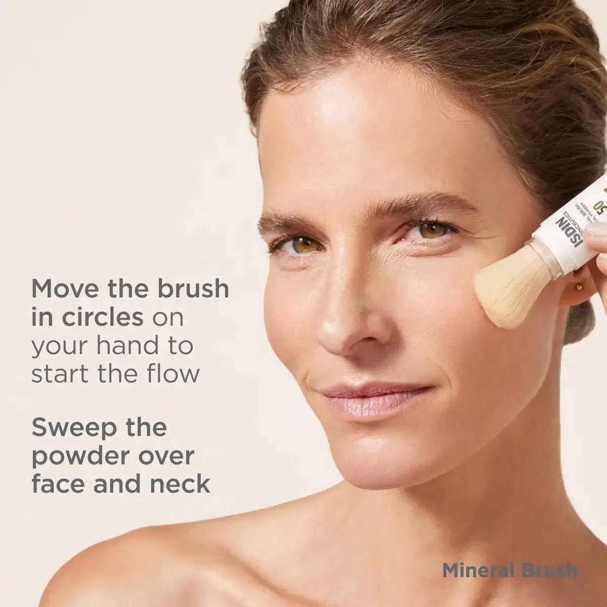 Woman with healthy-looking skin demonstrating moving the brush in circles and sweeping powder over face and neck for ISDIN Mineral Brush SPF 50 application. 