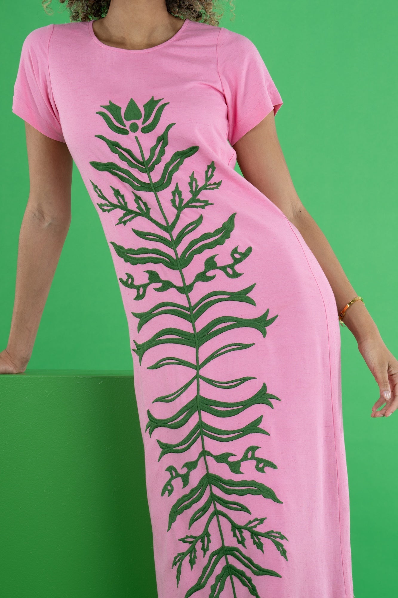 Close-up of the Emily McCarthy Cornelia Dress in Rosé, highlighting the round neckline and dark green floral appliqué.