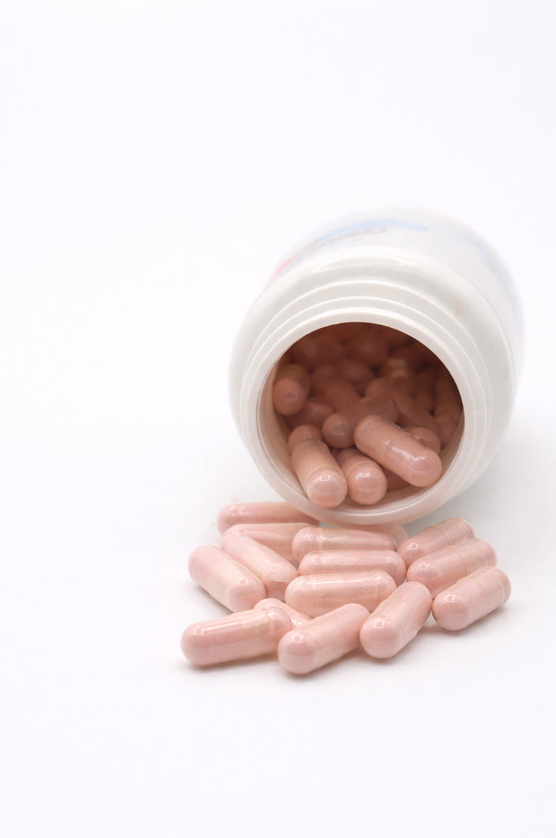 Pink Cooper Complete Vitamin B12 Methylcobalamin 1000 mcg capsules spilling out of an open white container on a white background