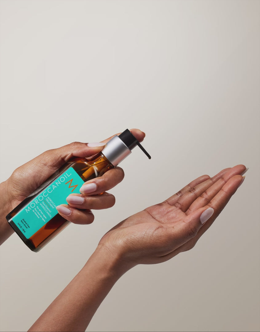 Moroccanoil Treatment Original application demonstration showing the hair oil dispensed from the pump into the palm before styling.